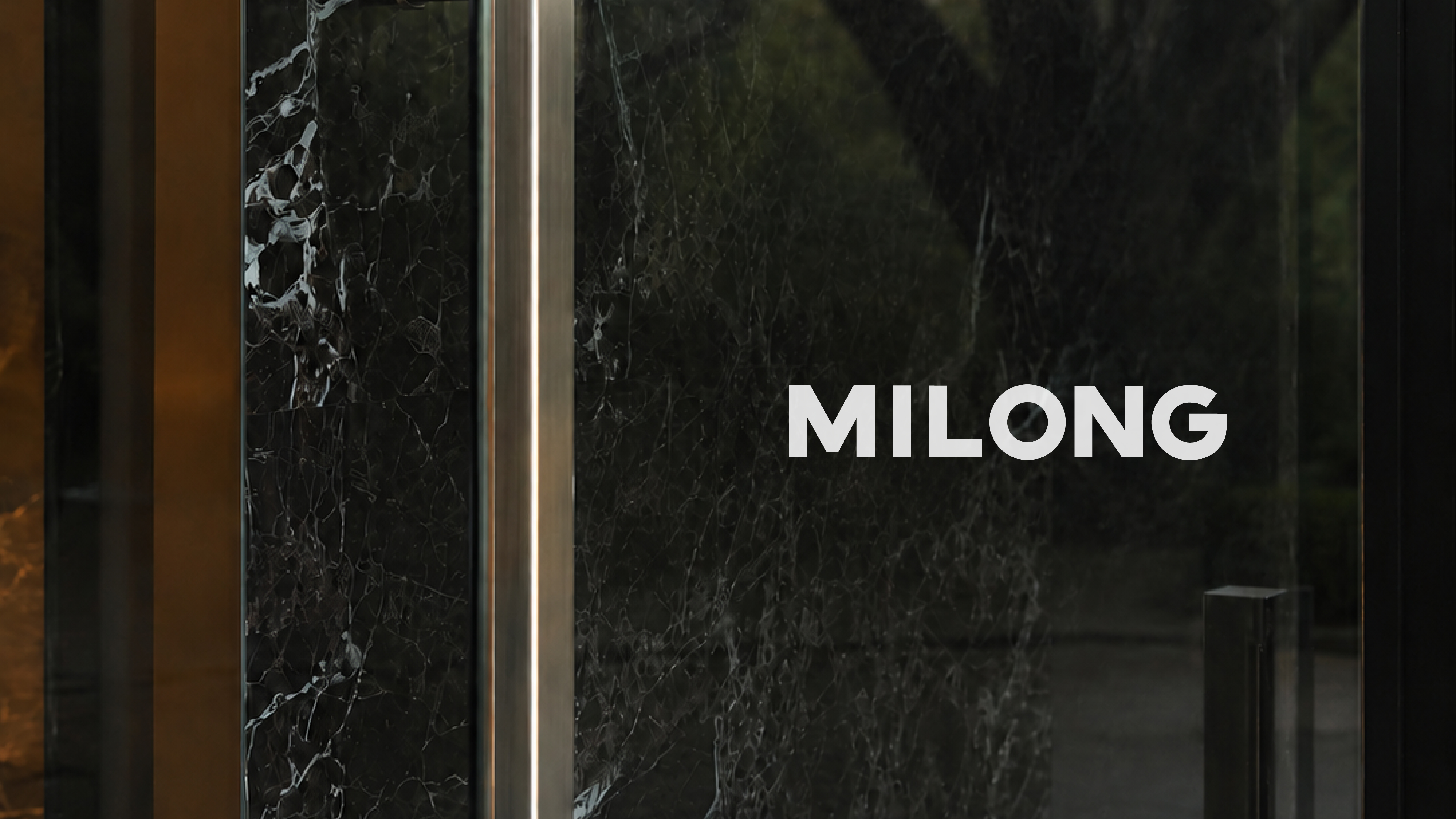 MILONG Latin wordmark on a dark glass door